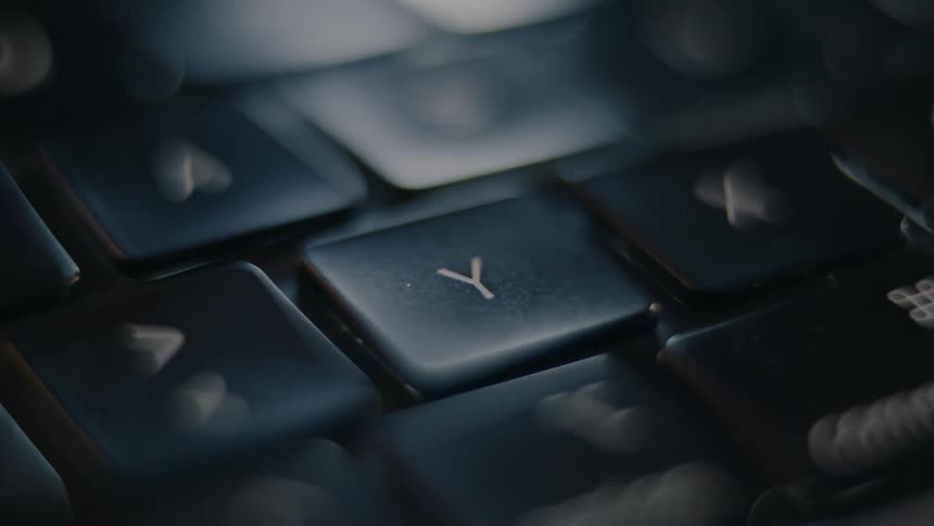 A close up of a keyboard with a soft focus centers on the y key which is then pressed twice by a finger