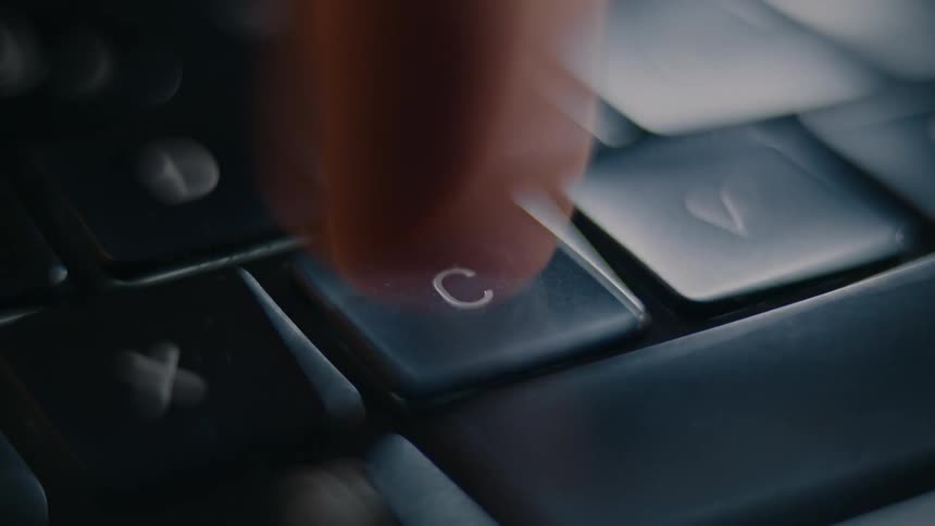 A finger pressing the c key on a keyboard