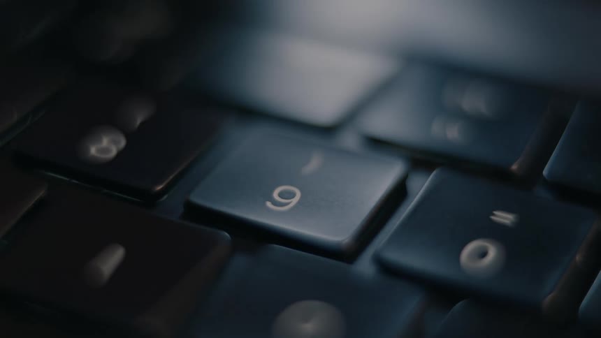 A finger pressing the 9 key on a keyboard