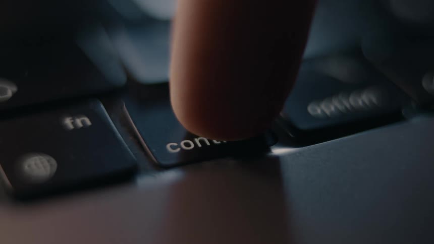Close up of a finger pressing a key on a laptop keyboard