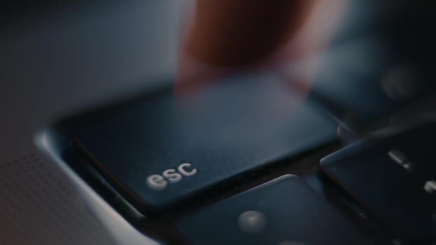 A person is frantically pressing a key on a computer keyboard