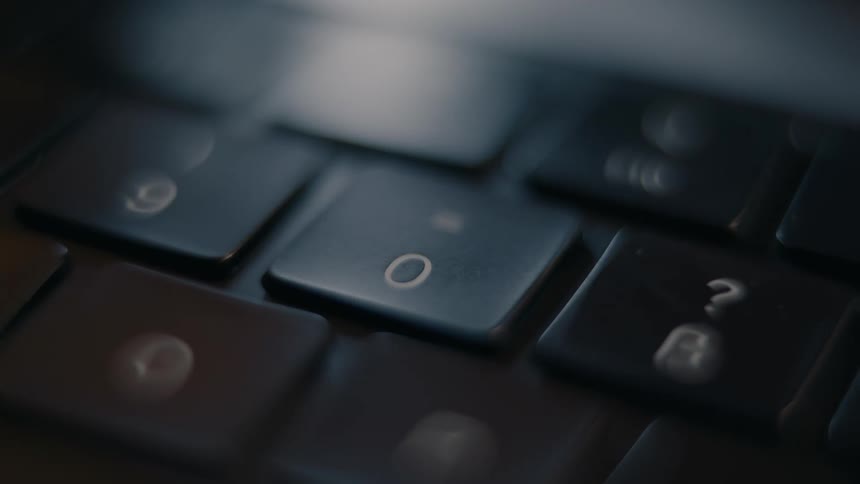 A finger pressing the zero key on a keyboard
