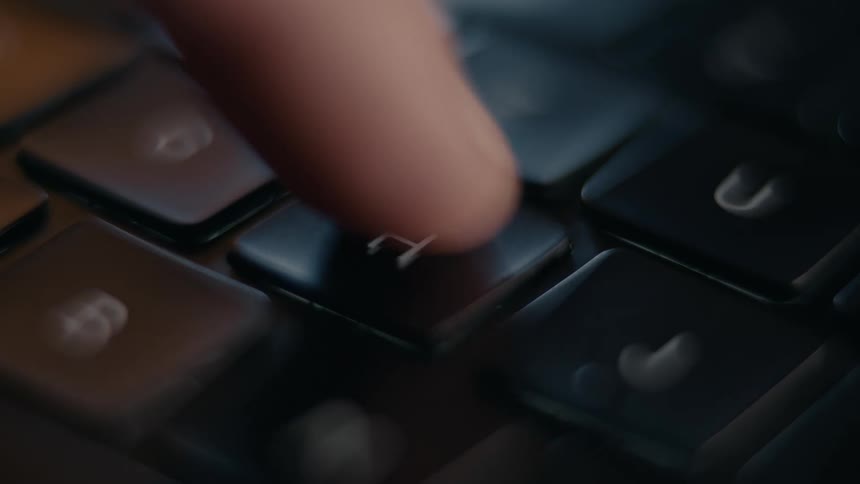 A blurred extreme close up of a keyboard shows the h key which is then pressed by a finger