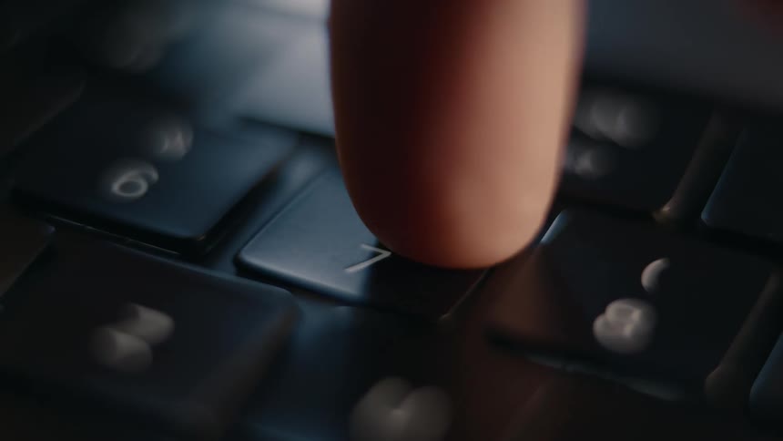 Finger clicking the number 7 key on a laptop