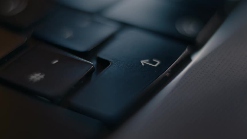 A person presses the enter button on the laptop
