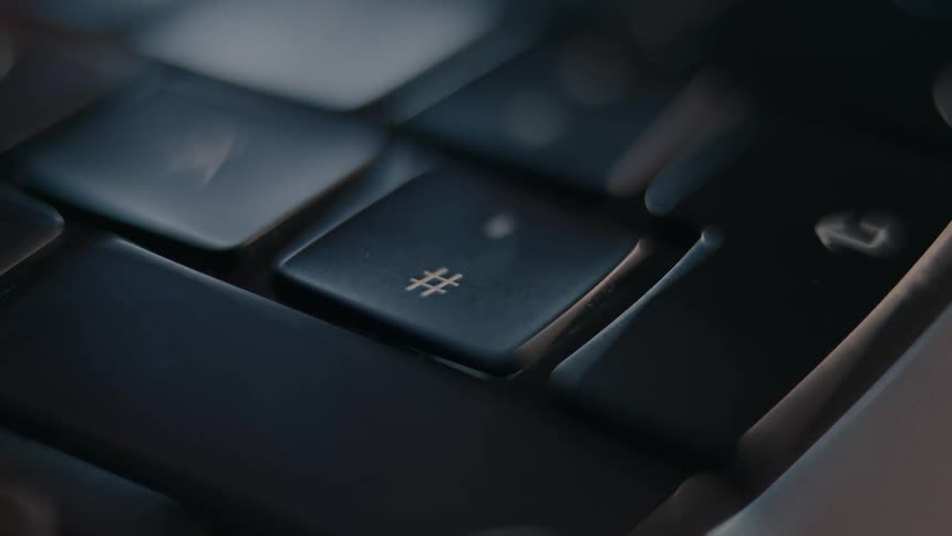 A finger pressing the hashtag key on a keyboard
