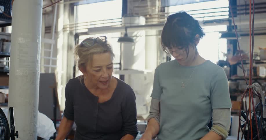 Two women work together with sheeting in a workshop