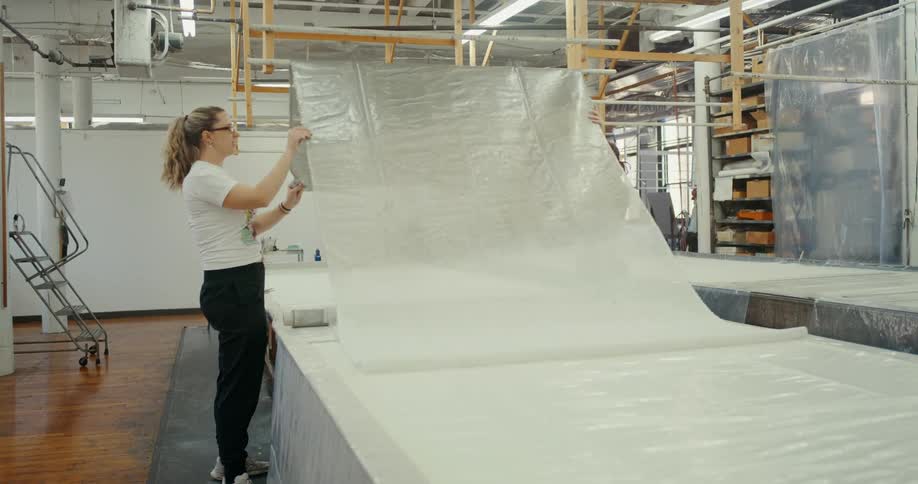 Two women adjusting fabric in a factory