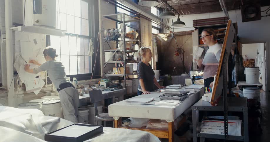 Women talk and laugh as they stand in a workshop