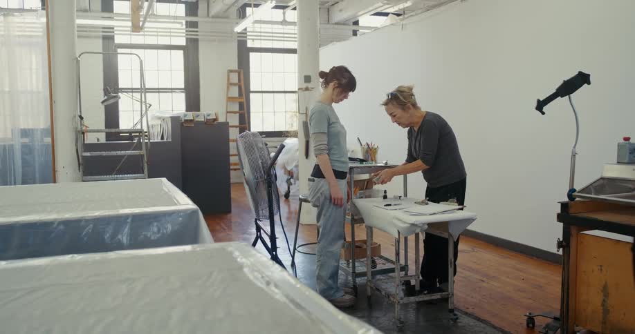 Two women in a textile factory interacting with tools