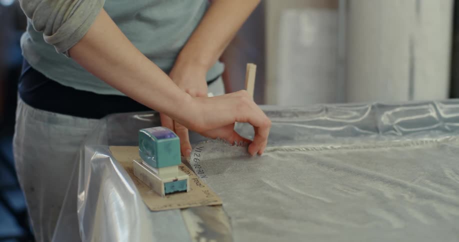 Pair of womans hands working on a surface with a plastic and ruler