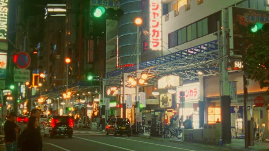 A busy urban street at night with illuminated neon signs and billboards in japanese