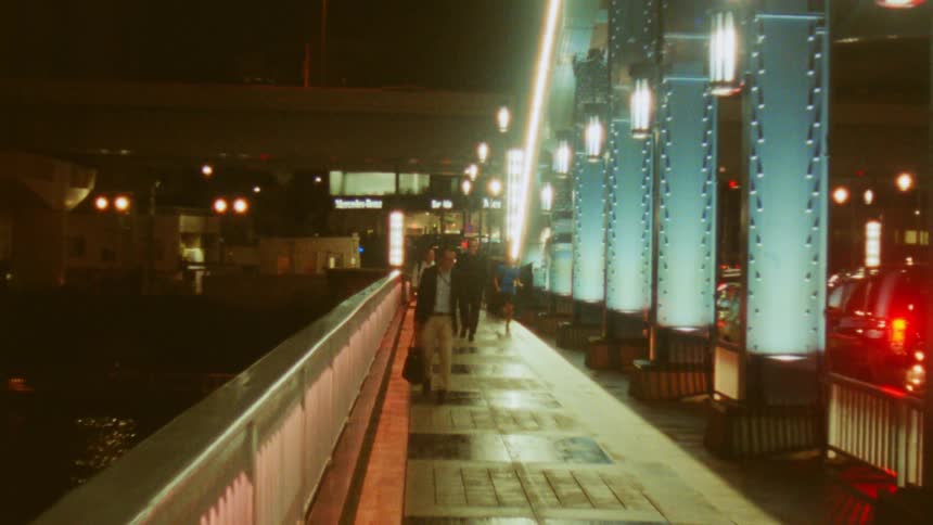 Men walk across a bridge over a river as a jogger runs past them