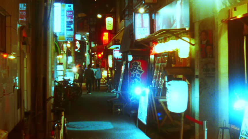 People walking down an asian alley at night with lights and restaurant storefronts