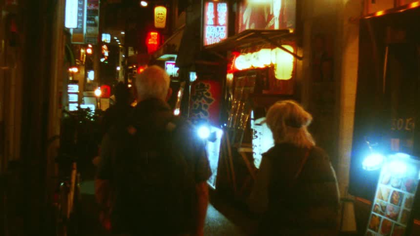People walk along a narrow street full of businesses