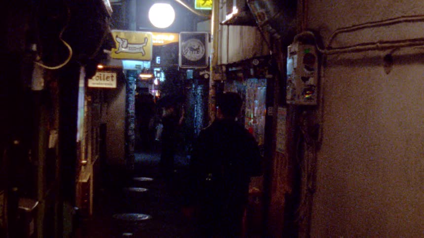 People walk down the dark alley