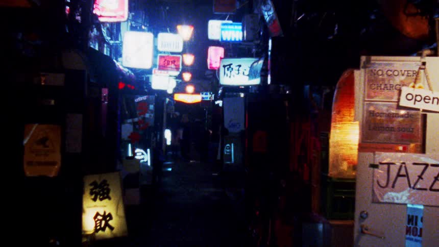 Alley in an asian city with some pedestrians walking at night