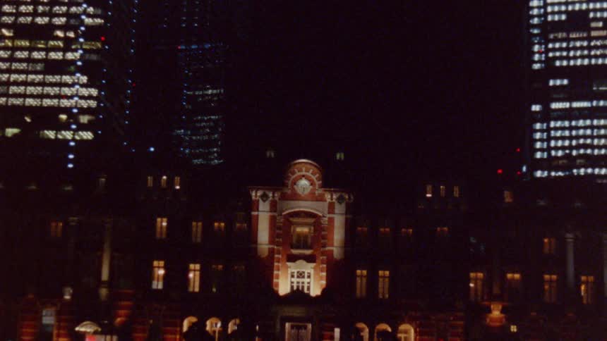 People walk in the dark past the complex in the city