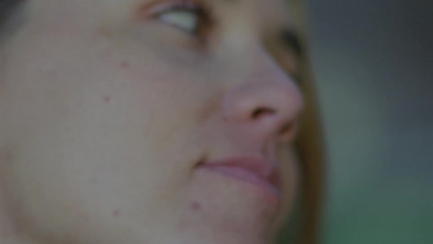 A woman looks upset as she looks around and a man puts his face to hers