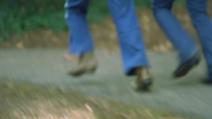 A couple of women running on a path in a park holding hands