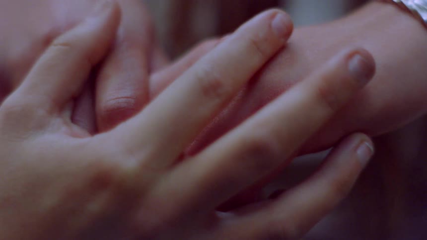Women rub each others hands as they hold hands