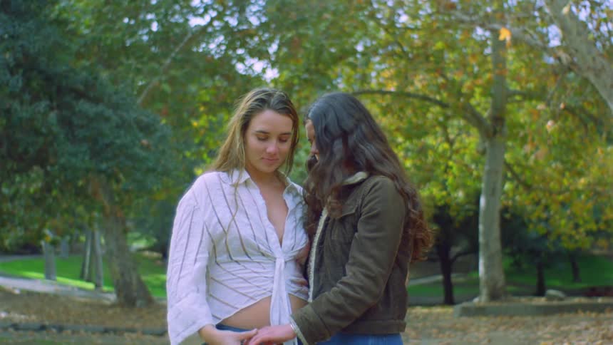 A female couple hugging and holding hands on a park
