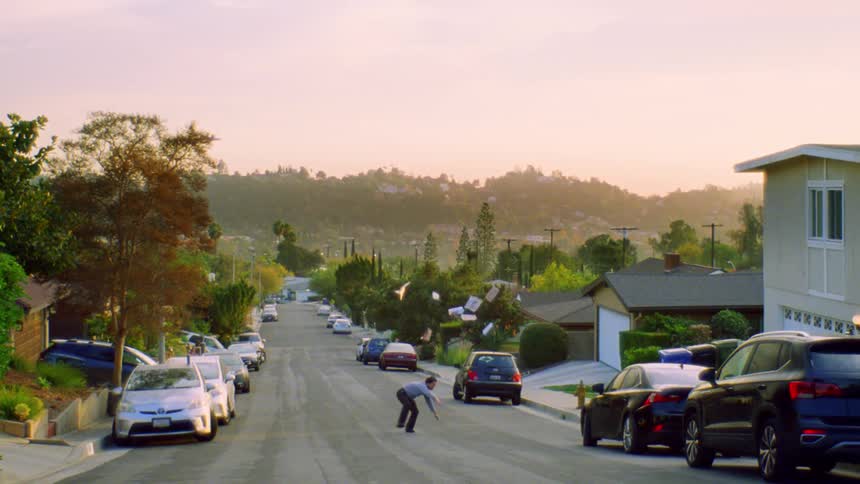 A man throws papers in the air as he dances in the street