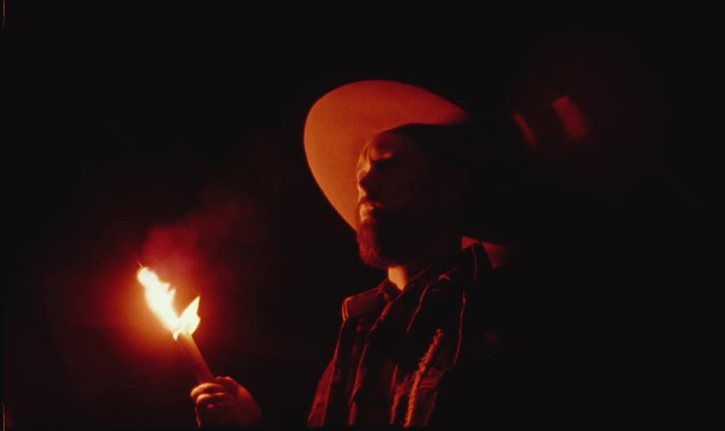 Man in hat holding a firework at night