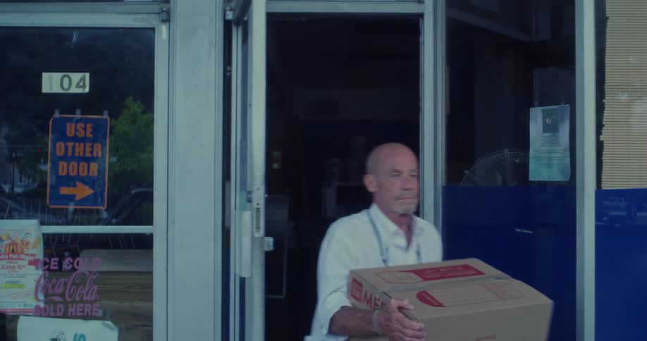 Man leaving a convenience store holding a large box