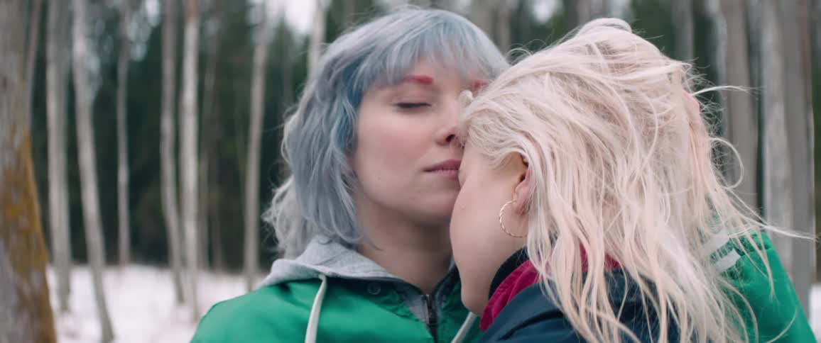 Two women hugging and caressing each other while standing in a forest