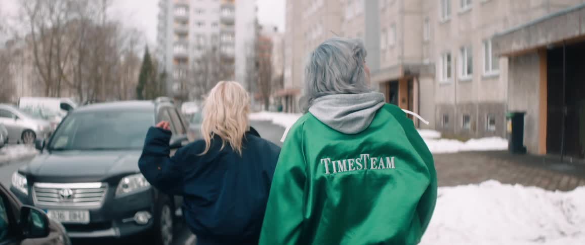 Two young women in coats walk outdoors through the snowy city