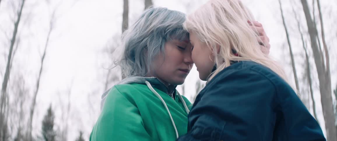 Two women put their heads together with eyes closed for a moment then look up