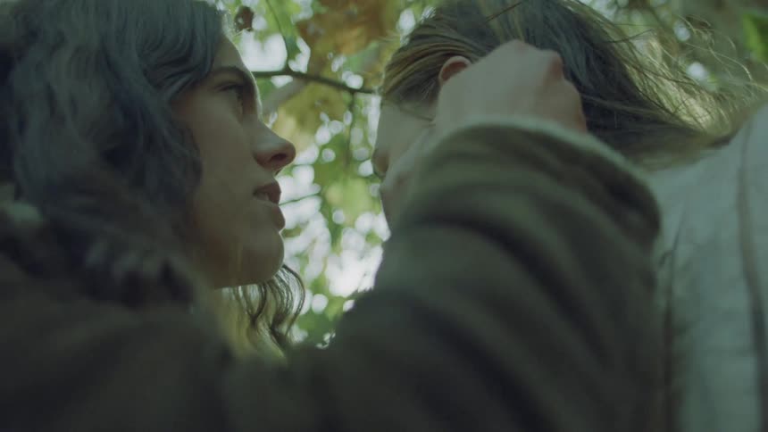 Two women under a tree romantically running their hands through each others hair