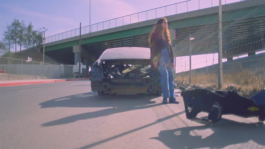Woman leaning thoughtfully against an abandoned car