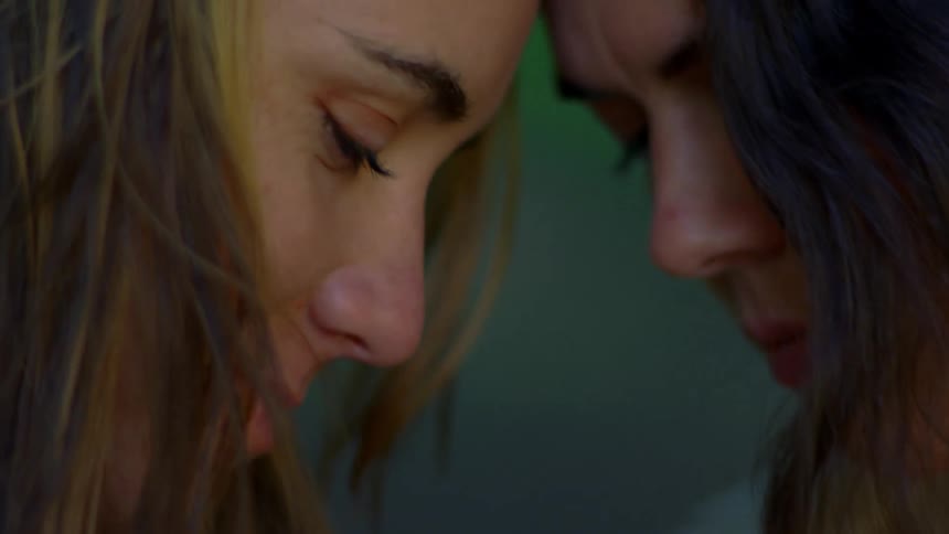 Two women lean together and smile