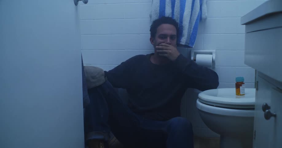 A man is sitting on the floor of a bathroom