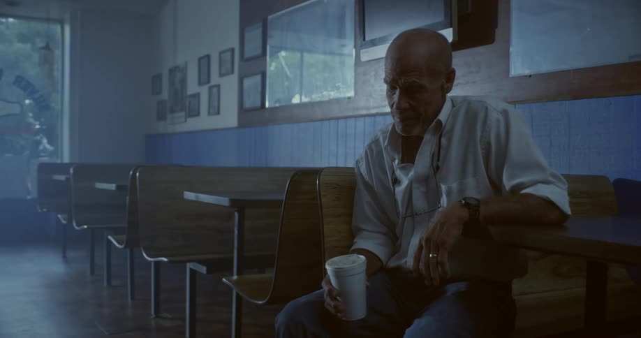 A man is sitting in a restaurant drinking from a cup