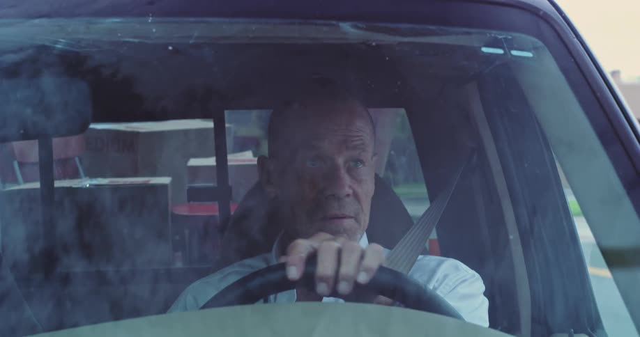 A man is driving a pickup truck during the day