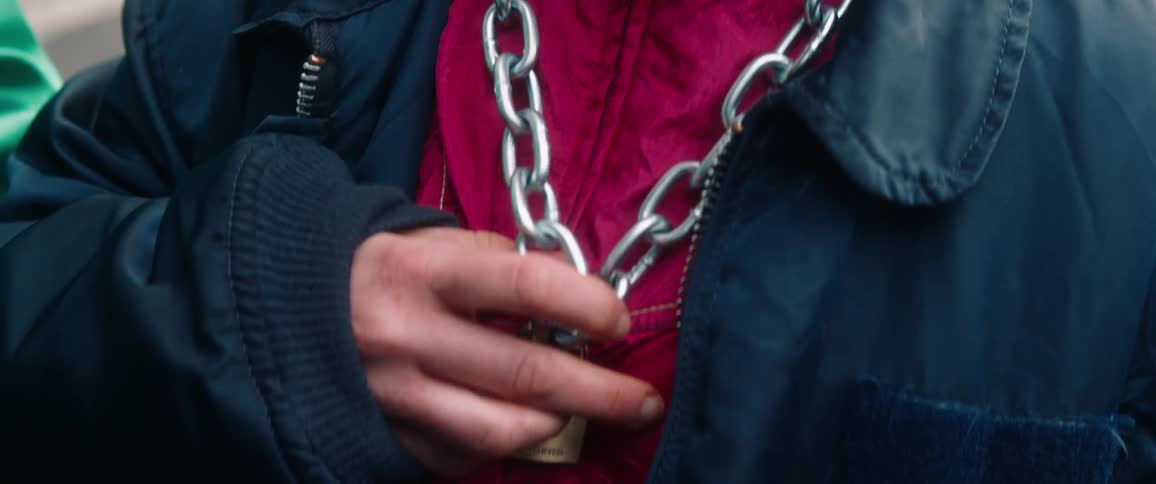 A woman wearing a heavy chain around their neck with a padlock securing it