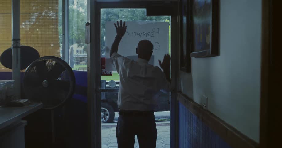 A man puts a sign on the restaurant door
