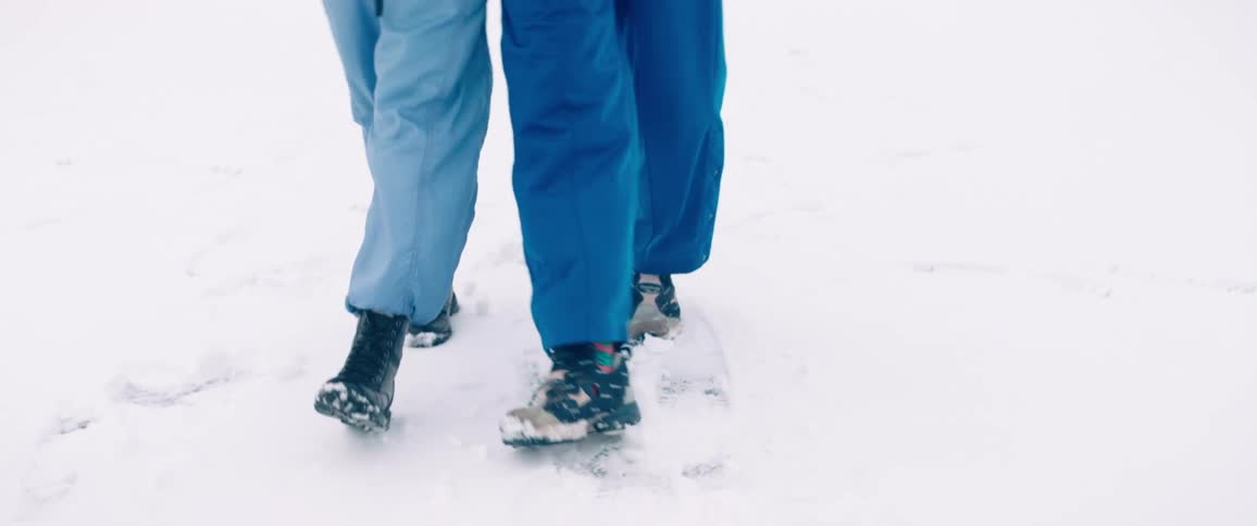 Two people walk close together through the snow