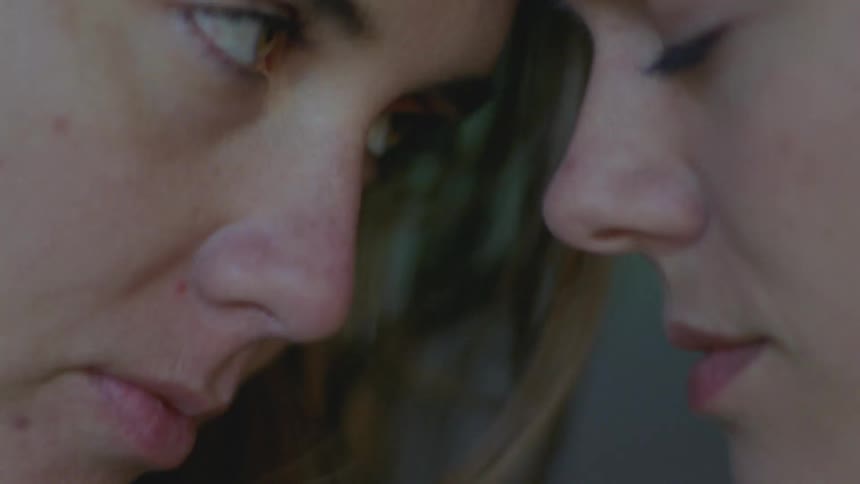 Two women lean their heads together