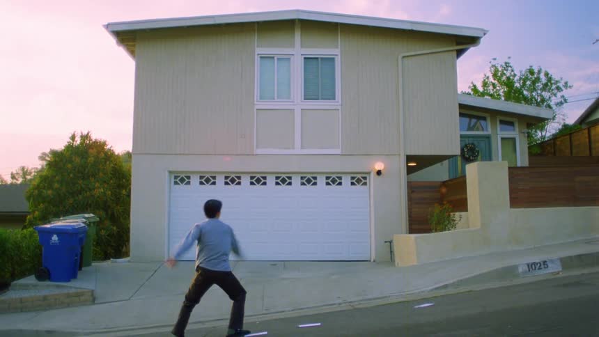 Man dancing in front of a house and playing cards