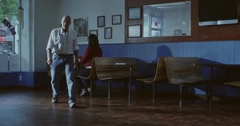 A man gets up from the table in the restaurant and walks away