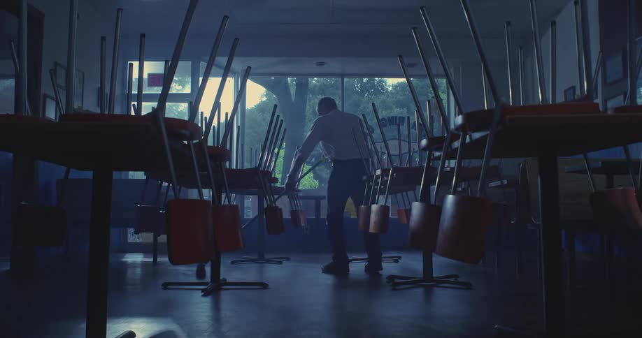 Man silently cleans the floor of an empty restaurant