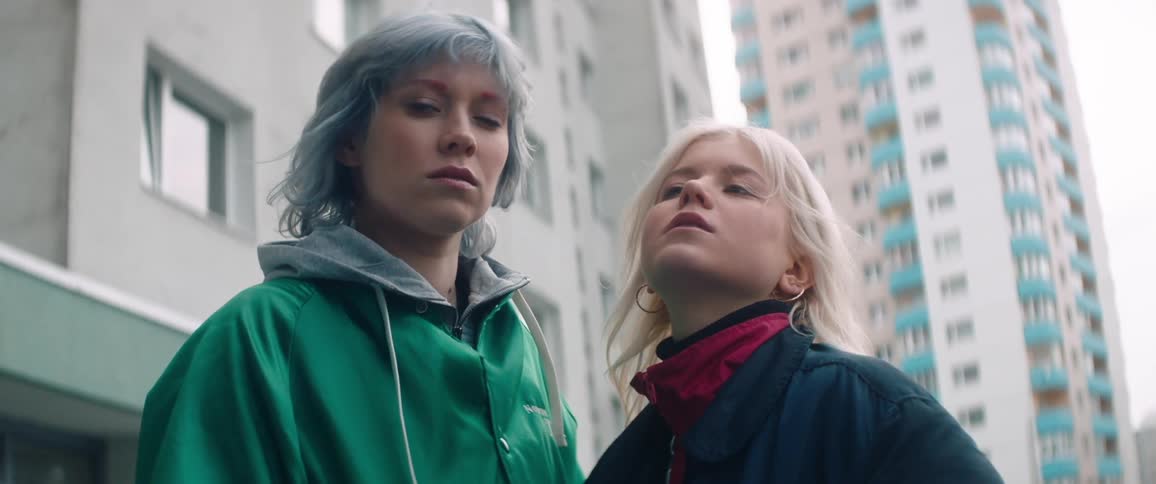 Two women look at each other by the buildings