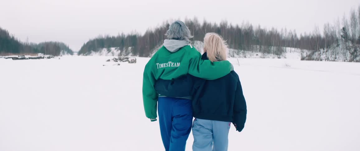 Two people walk arm in arm across a vast snowcovered landscape