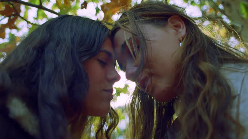 Two women lean their heads together and laugh