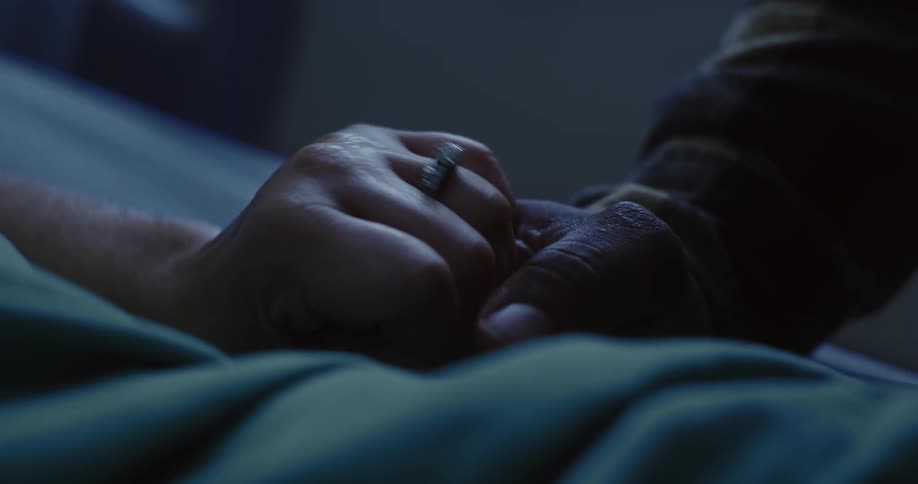 Two people hold hands tightly