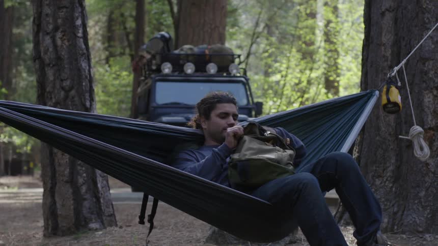 Man setting up camp near his vehicle in the woods